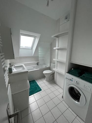 Appartement Nuage blanc في بيتش: حمام مع مغسلة وغسالة ملابس