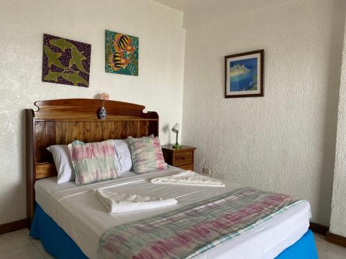 Schlafzimmer mit einem großen Bett mit einem Kopfteil aus Holz in der Unterkunft Camiguin Island Golden Sunset Beach Club in Mambajao