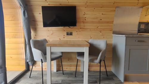 a table with two chairs and a tv on a wall at Devonknowes lodges in Tillicoultry