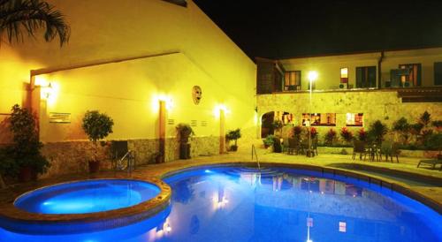 a swimming pool in front of a house at night at Adventure Inn in San José