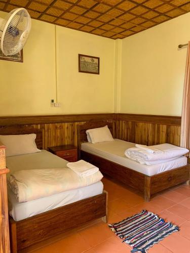 two twin beds in a room with a fan at Zuela Guesthouse in Louang Namtha