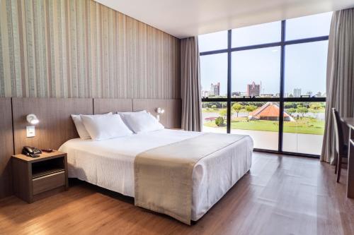 トレドにあるBello Hotelのベッドと大きな窓が備わるホテルルームです。