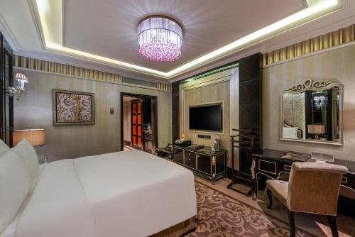 a bedroom with a bed and a desk and a tv at Narcissus Riyadh Hotel & Spa in Riyadh