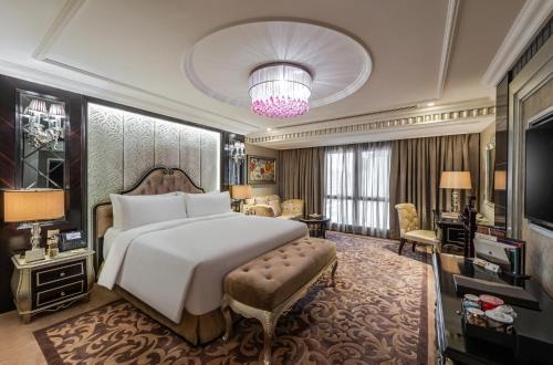a bedroom with a large bed and a living room at Narcissus Riyadh Hotel & Spa in Riyadh