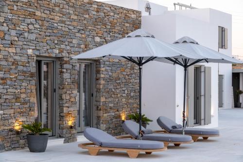 a row of lounge chairs and an umbrella at Golden Bay luxury villas and suites in Chrissi Akti