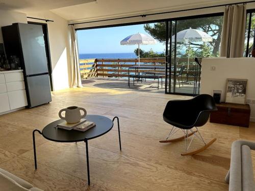 a living room with a table and a chair and the ocean at Cabanon moderne, les pieds dans l'eau, 2 chambres in Le Pradet