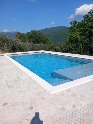 a swimming pool with blue water and mountains in the background at Agriturismo Il Casaletto in Montefranco