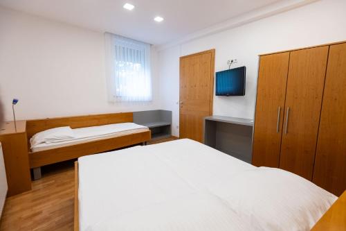 a bedroom with two beds and a tv and cabinets at Apartmaji in sobe RaMar in Straža