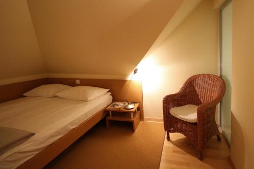 a small bedroom with a bed and a chair at Apartments Villa Boltez in Kranj