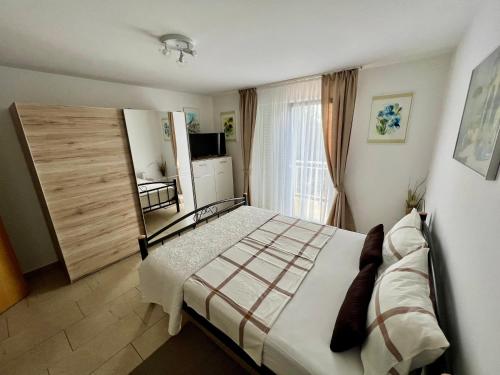 um quarto com uma cama grande e uma janela em Apartmani Fortuna em Lumbarda
