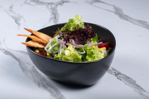 a black bowl of salad and fries on a counter at Kalkan Saray Suites Hotel in Kalkan