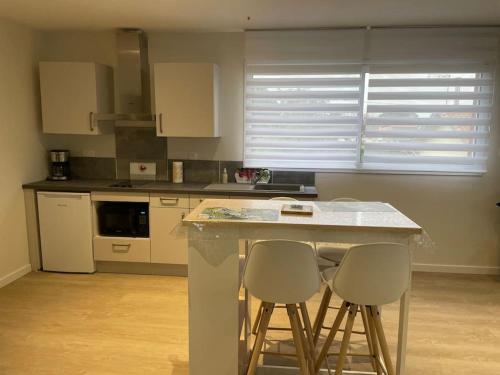 a kitchen with two bar stools and a counter top at Chez ERIC in Villeneuve-du-Paréage