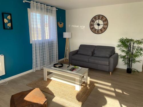 a living room with a couch and a clock on the wall at Chez ERIC in Villeneuve-du-Paréage