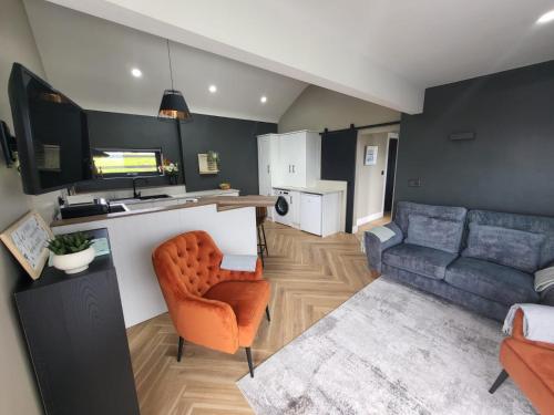 uma pequena sala de estar com um sofá e uma cozinha em Rose Meadow Lodge em Liscannor
