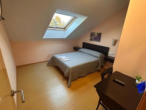 1 dormitorio en el ático con cama y ventana en HOSTAL RESTAURANTE AQUA, en Ourense