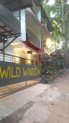a wild window sign in front of a building at Wild Window - Forest View Homestay in Thekkady