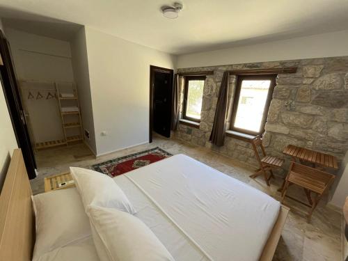 a bedroom with a white bed and a stone wall at AGON Ephesus in Selcuk