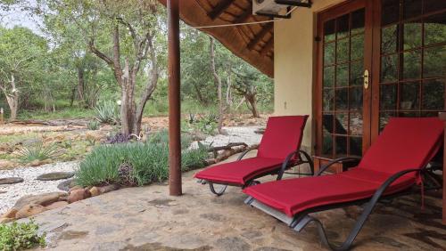 two red chairs sitting on the porch of a house at Bona Intaba Game Lodge in Hoedspruit