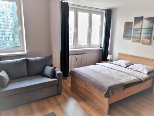 a bedroom with a bed and a couch and windows at Warsaw strict center, WiFi, next to central railway station, Złote Tarasy, PKiN, Warszawa ścisłe centrum in Warsaw