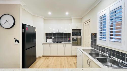 a kitchen with white cabinets and a black refrigerator at Peaceful Sanctuary in Pennant Hills