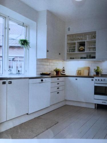 cocina blanca con armarios blancos y ventana en Room, central location, en Halmstad