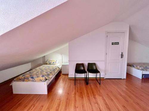 a bedroom with a bed and two black chairs at Ljmonade Hostel in Cascais