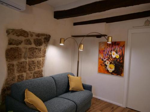 a living room with a blue couch and a painting at La Bartolomea Home & Suite in Pitigliano