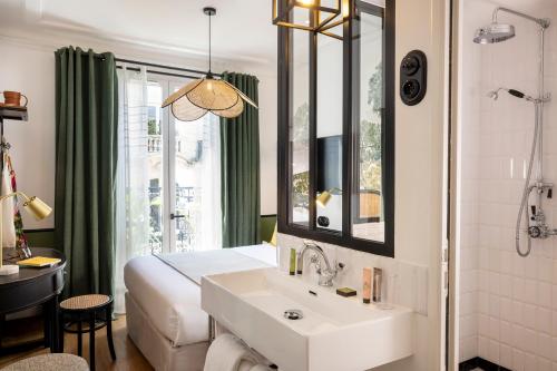 Avalon Cosy Hotel Paris في باريس: حمام فيه سرير ومغسلة ومرآة