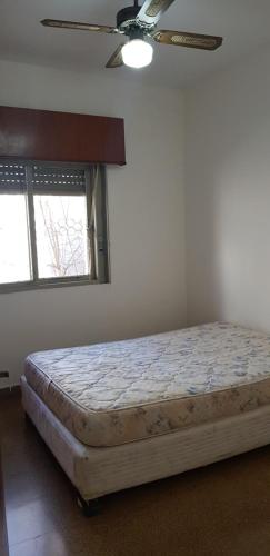 een bed in een slaapkamer met een plafondventilator bij BELLA CASA EN VILLA LIBERTAD in Leandro N. Alem