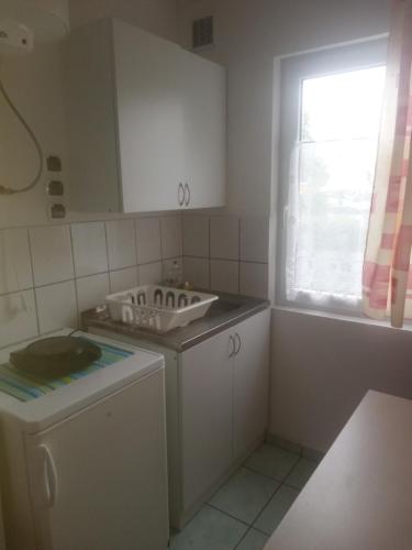 a kitchen with a sink and a washing machine at Domki letniskowe Aneta in Trzęsacz