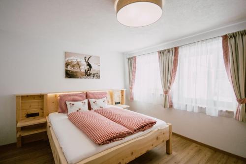 1 dormitorio con 1 cama con almohadas rojas y blancas en Nedererhof - Ferienwohnung Gamskar en Schmirn