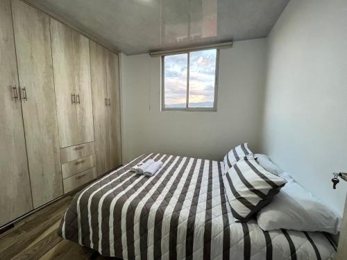 um quarto com uma cama com um edredão listrado e uma janela em El Mirador em Barbosa