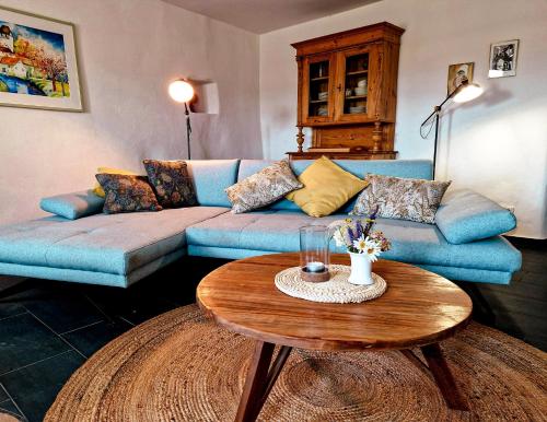 a living room with a blue couch and a table at Ferienhaus "Entenhaus" im Gutshaus De La Fontaine in Feilsdorf