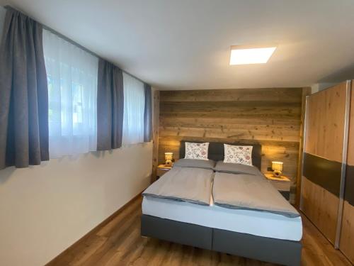 a bedroom with a bed and wooden walls at APARTMENT DACHSTEIN - neu im Haus Wieseneck in Ramsau am Dachstein