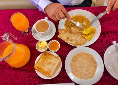 a table topped with plates of breakfast food and orange juice at HOTEL DE SMART Multan in Multan