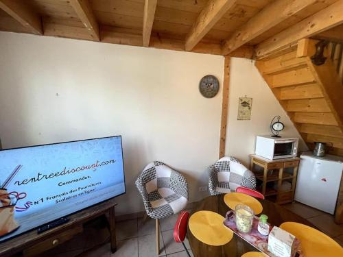 a living room with a television and a table and chairs at la p'tit marennaise in Marennes