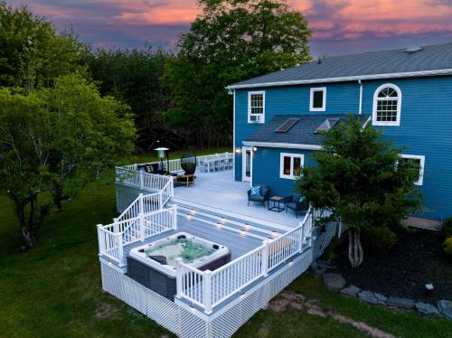 a large deck with a hot tub on a house at Mountain Blue Vista - Luxury retreat near Ski resorts with Pond, Firepit and Hot Tub in Windham