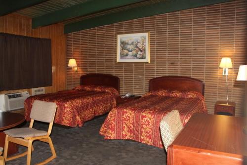 a hotel room with two beds and a table at Scottish Inn - Madison Heights in Madison Heights