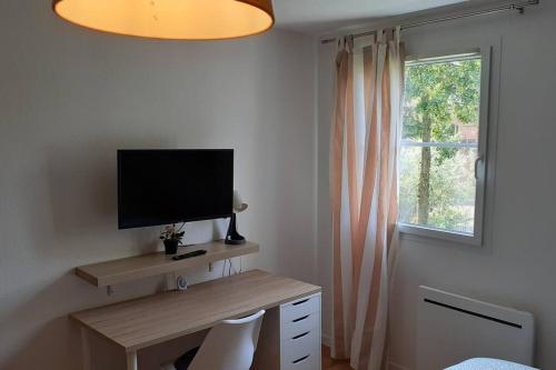 une pièce avec un bureau avec une télévision et une fenêtre dans l'établissement Studio meublé Mulhouse, à Mulhouse
