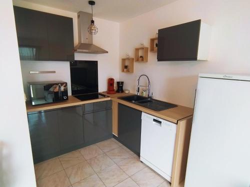 a kitchen with black cabinets and a white refrigerator at Appartement centre ville à deux pas de la plage in Le Grau-du-Roi