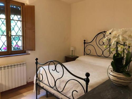 西恩納的住宿－LA VIGNA Agriturismo，一间卧室,配有一张床,桌子上放着花瓶