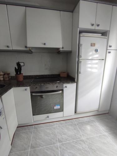 La cuisine est équipée de placards blancs et d'un réfrigérateur blanc. dans l'établissement Apartamento Casa Ryo, à Santander