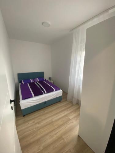 a bedroom with a bed with purple sheets and a wooden floor at Apartman MI in Banja Koviljača