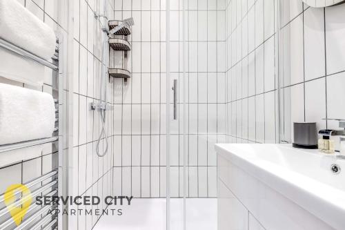 a white tiled bathroom with a sink and a shower at SCA - Entertaining Studio - CR6 in Birmingham
