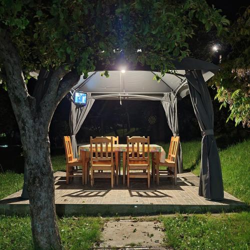 a table and chairs under a gazebo at night at Pensiunea Casa Madalina in Corbeni
