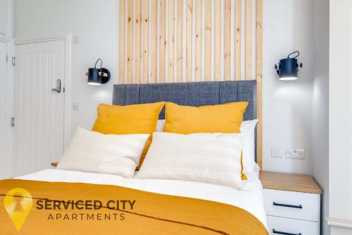 um quarto com uma cama com almofadas amarelas e brancas em SCA - Best Located Studio - CR1 em Birmingham