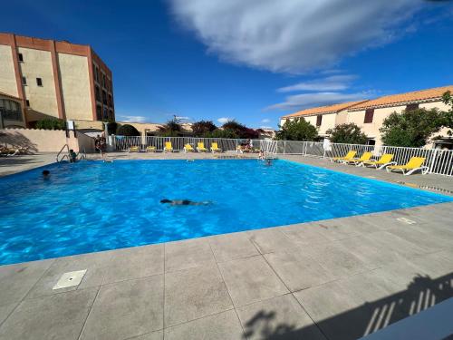 une grande piscine avec de l'eau bleue et des chaises dans l'établissement Azur, au Barcarès