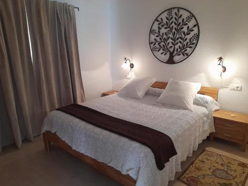 a bedroom with a bed with white sheets and a clock on the wall at 200 m playa, WiFi, TV SAT, BBQ in Pilar de la Horadada
