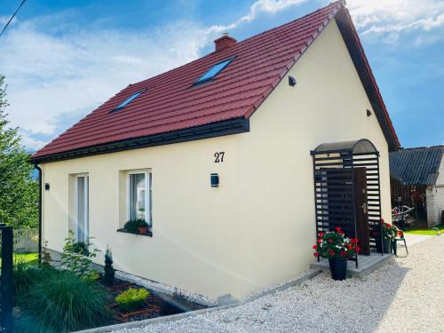 a small white house with a red roof at Domek Przy Osadzie in Bieliny