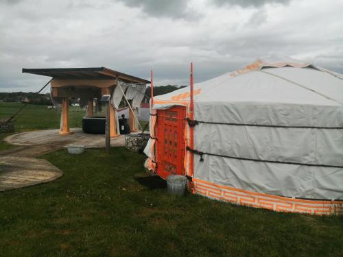 uma tenda sentada na relva ao lado de um edifício em La ferme autour du Grain em Bouglainval